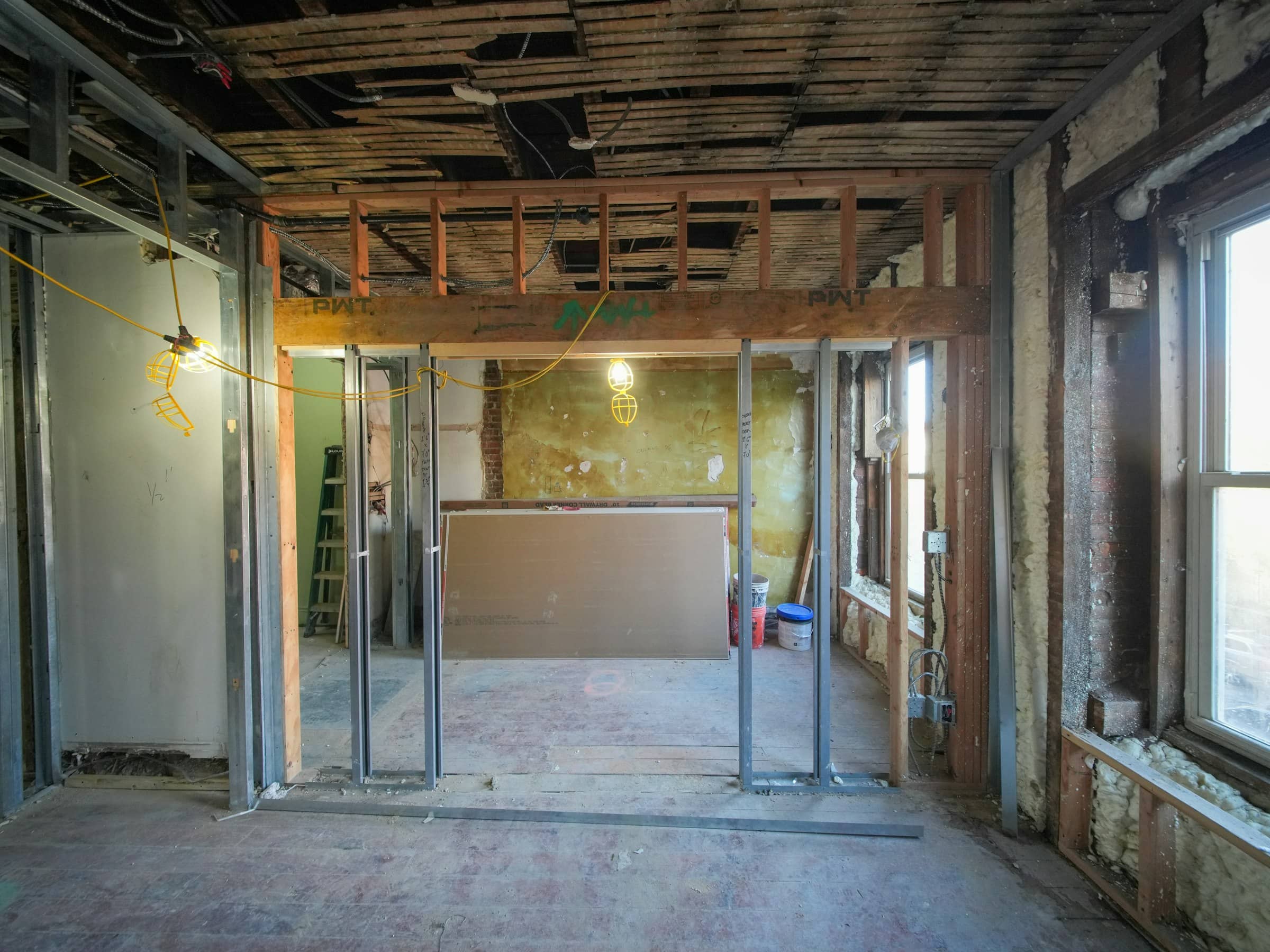 Interior of a home being rebuilt after disaster damage, showing exposed framing, metal studs, drywall, and insulation during reconstruction